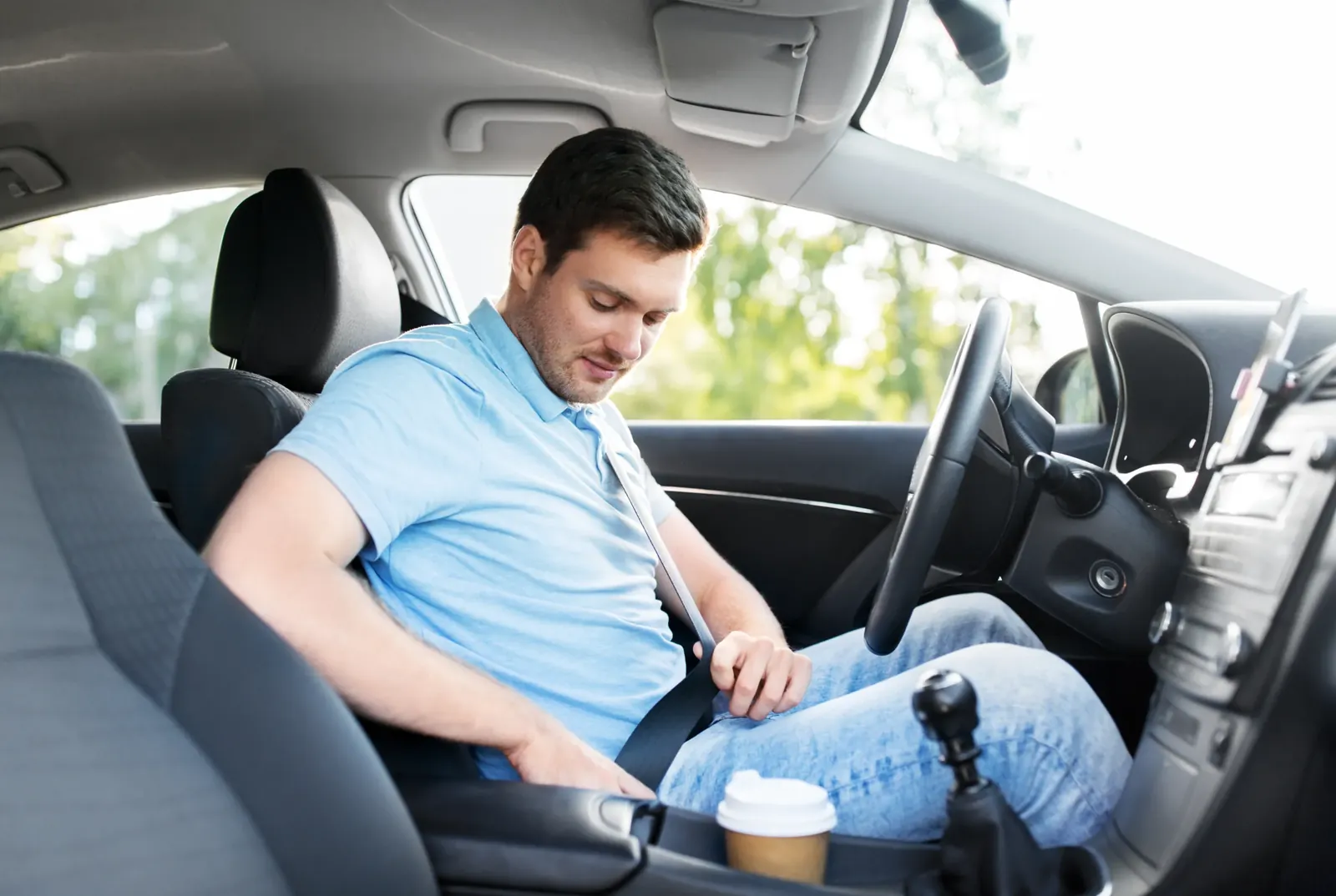Driver fastening a seat belt in a working vehicle cabin before starting a shift.