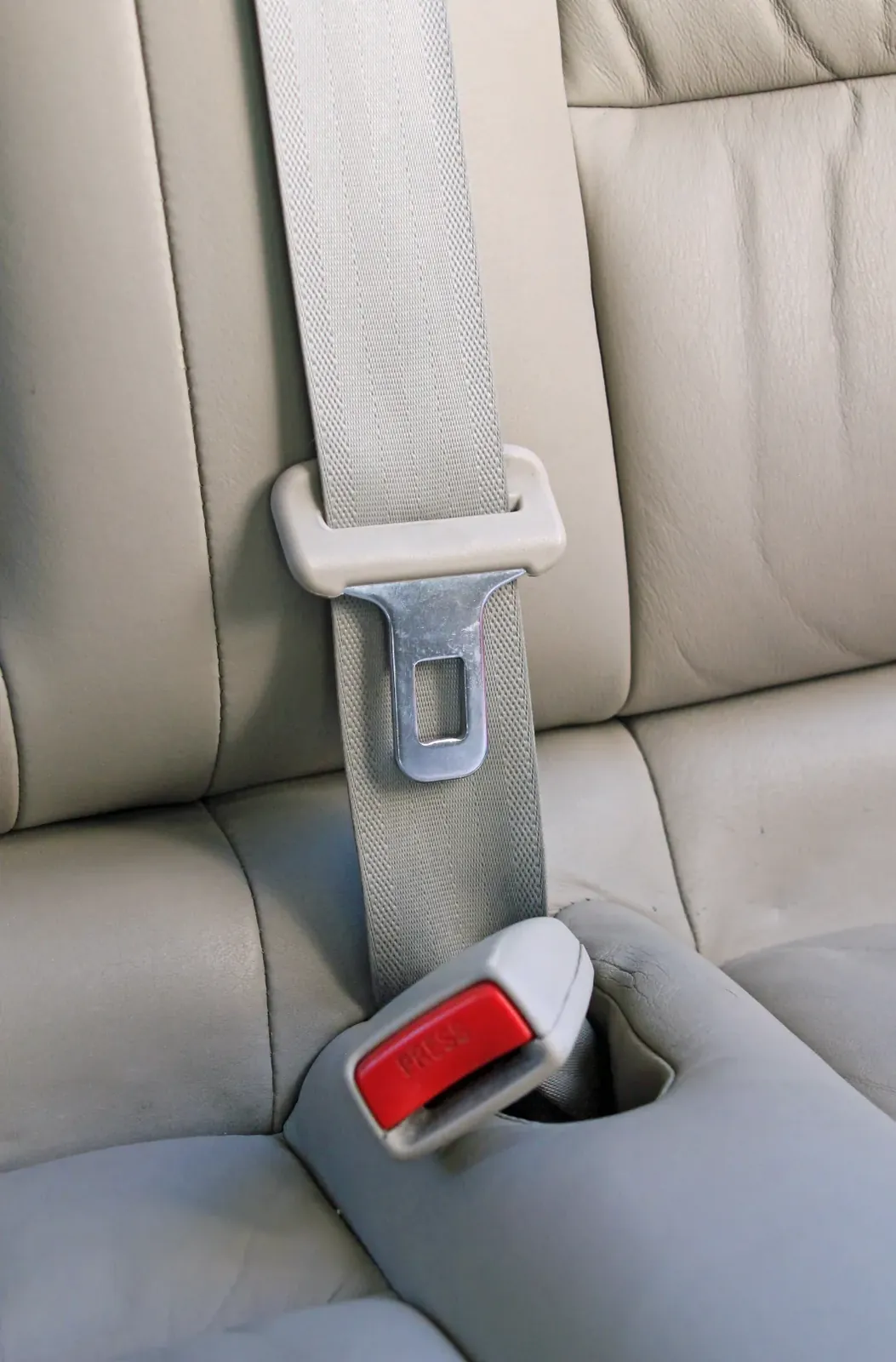 Seat belt assembly fitted to a rear vehicle seat, showing the webbing running down into the buckle at the seat cushion.