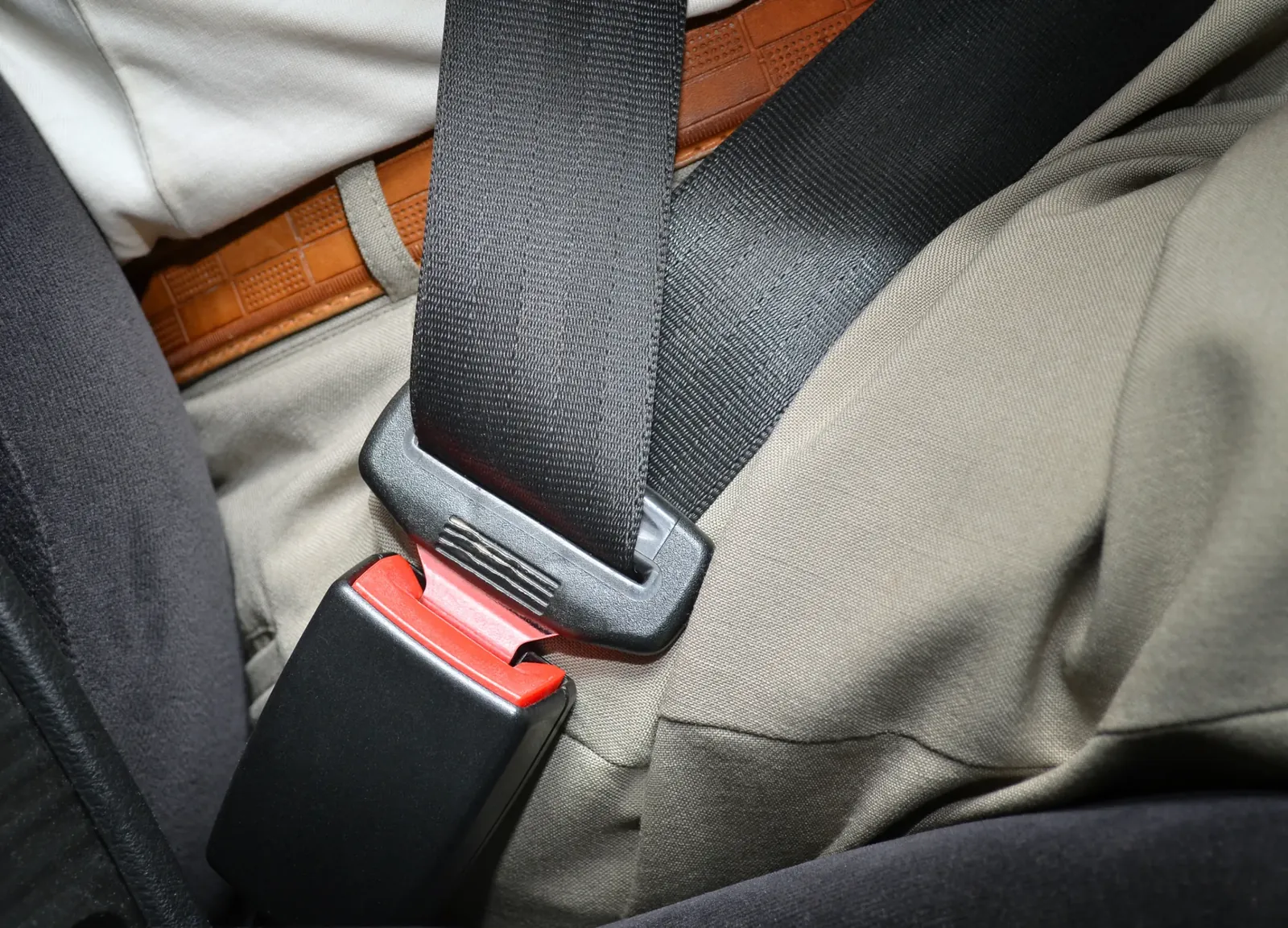 Seat belt buckle and latch sitting against the seat cushion, showing how the hardware integrates with the seat.